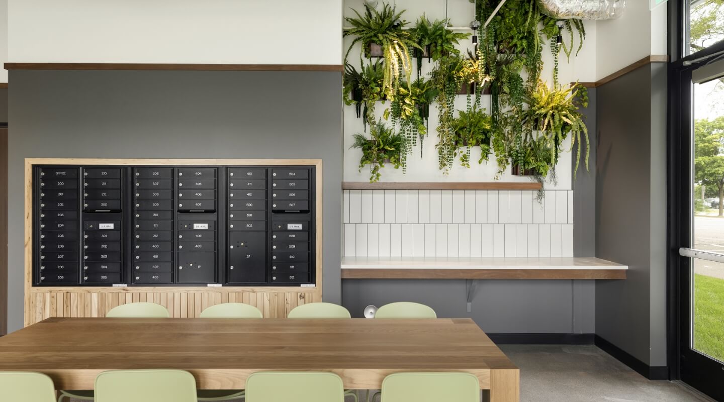 Modern mailroom with secure mailboxes and a green wall installation.