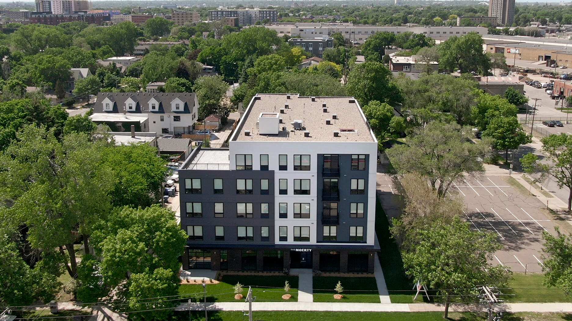 Aerial view of a modern apartment building in a green urban area.