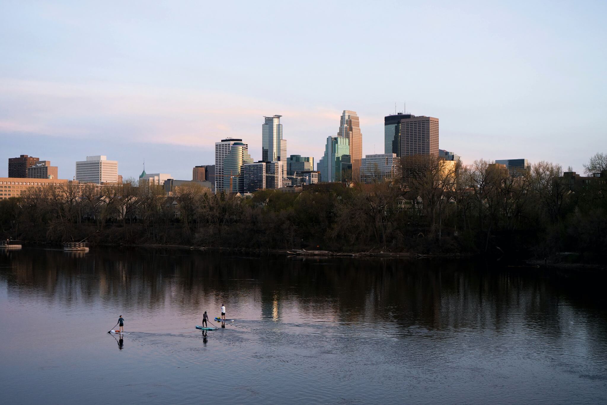  Twilight cityscape of Minneapolis with paddle boarders on the water.
